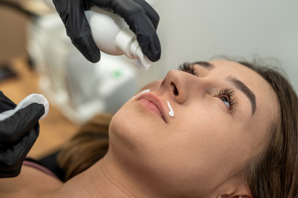 师父在上唇脱毛后涂抹舒缓霜。图片下载