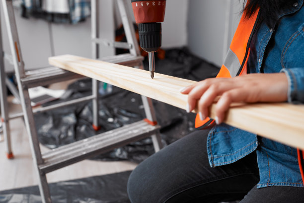 一个女人的手在建筑工地上钻木板的特写图片下载