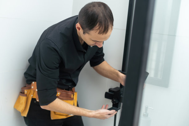 工人正在用一根金属棒连接淋浴房的玻璃墙。图片下载