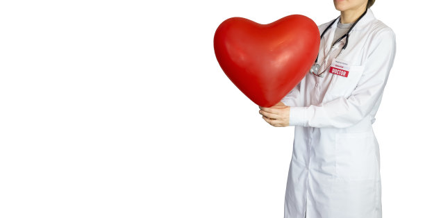 医生穿着白大褂，手里拿着一颗白色背景的大红心。图片下载