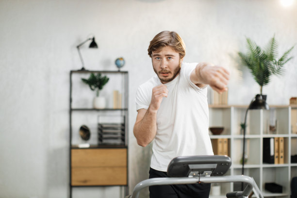 年轻有吸引力的运动男子在白色t恤做拳击拳头，同时有早上锻炼图片下载