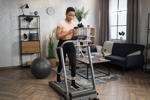 侧视图的运动健身女性在粉红色t恤上敲击智能手机的屏幕图片下载