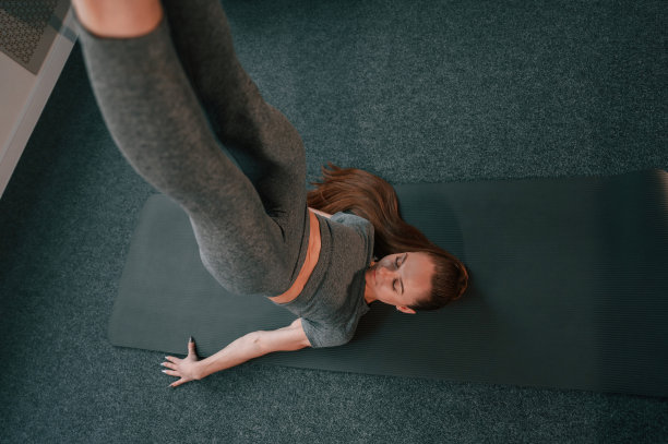 双腿向上的体式。年轻女子在瑜伽服做健身室内图片下载
