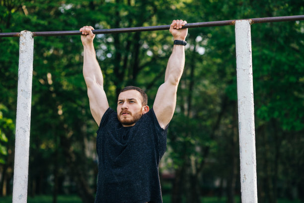强壮的肌肉大胡子男子做俯卧撑在酒吧在户外圣图片下载