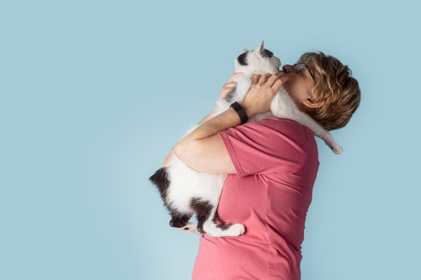 一名白人妇女抱着一只曼岛猫，这只猫正抱着她图片下载