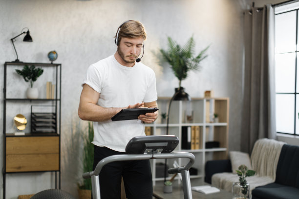 有吸引力的年轻体育白人商人在耳机工作与平板电脑，而工作图片下载