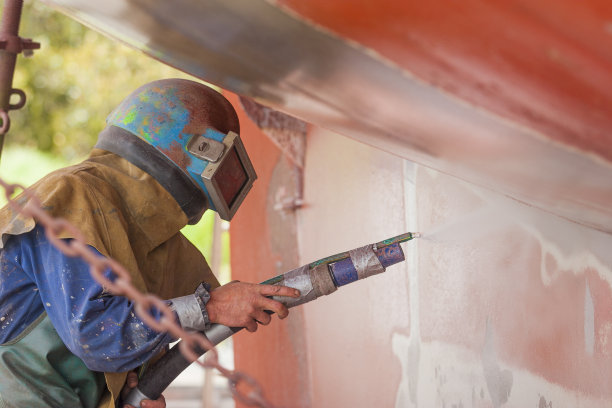 一名工人正在对锈蚀的船体进行喷砂处理图片下载