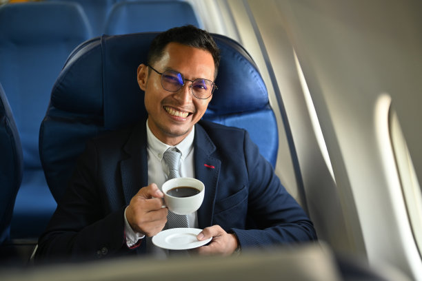 积极的商务旅客坐在机舱里喝咖啡。商务或出国旅游的概念。图片下载