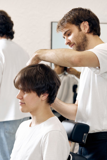 理发师坐在椅子上与白人男子交谈图片下载