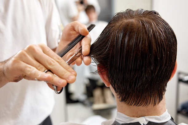 年轻的白人男子理发由专业的男性发型师图片下载