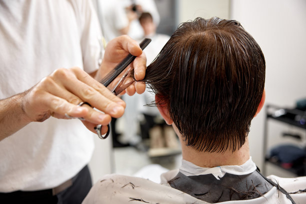 年轻的白人男子理发由专业的男性发型师图片下载