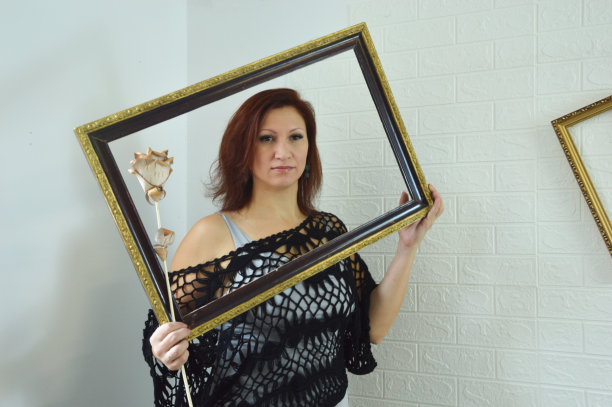 一名年轻女子手里拿着木玫瑰和一根法棍，看着相机。一个女孩的肖像在一个相框上的白色背景。图片下载