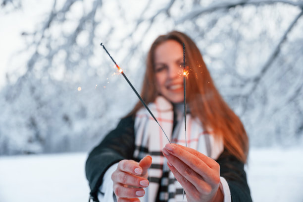 手持新年烟花。一个美丽的年轻女子在冬天的森林里图片下载
