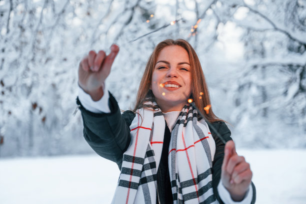 手持新年烟花。一个美丽的年轻女子在冬天的森林里图片下载