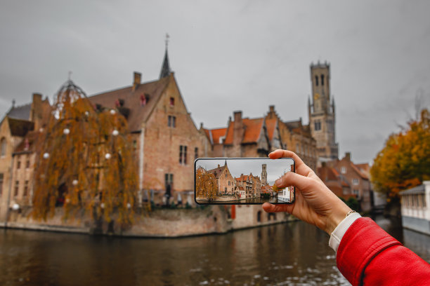 一名游客用手机拍摄比利时布鲁日的历史建筑和运河图片下载