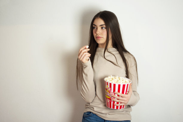 年轻漂亮的女人拿着一桶爆米花图片下载