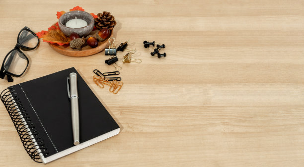 螺旋记事本，一支钢笔和秋叶放在木桌上图片下载