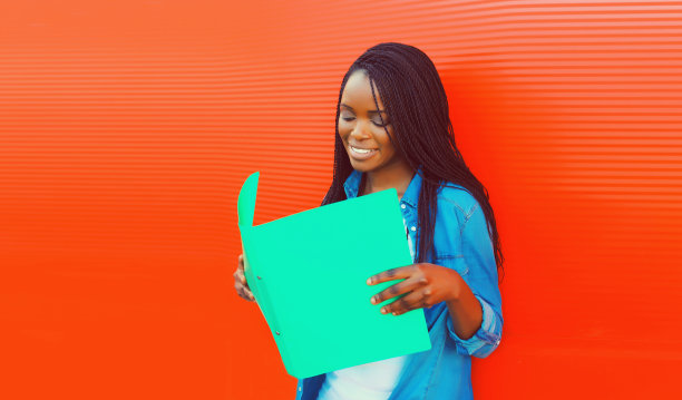 快乐微笑的年轻非洲妇女的肖像与文件夹上的红色背景图片下载