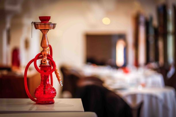 特写的红色水烟与玻璃烧瓶在木制表面的咖啡馆与模糊的背景图片下载