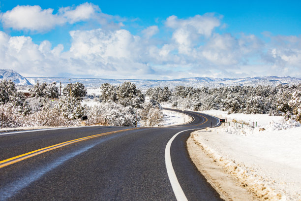 开阔的乡村道路被雪包围，背景是雪山图片下载