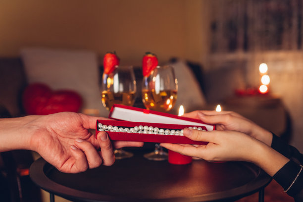 红色礼盒与珍珠项链。情人节的情侣在家共进浪漫晚餐时交换礼物。图片下载