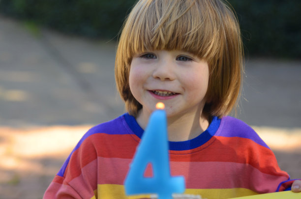 儿童生日，男孩和带有4号蜡烛的生日蛋糕的合影图片下载