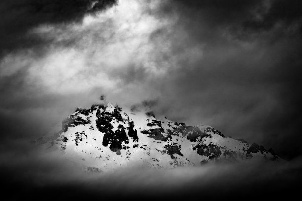 在寒冷的天气里，一座被雪覆盖的山的灰度镜头。图片下载