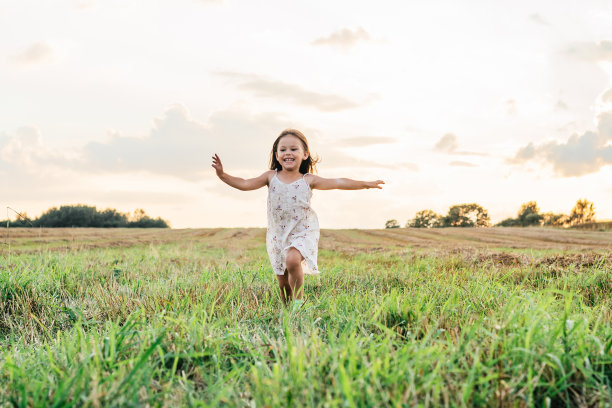微笑的小女孩快乐地跑过田野。草地上快乐无忧无虑的孩子。户外散步。图片下载