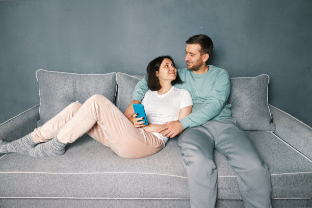 微笑的男人拥抱在沙发上放松的妻子图片下载