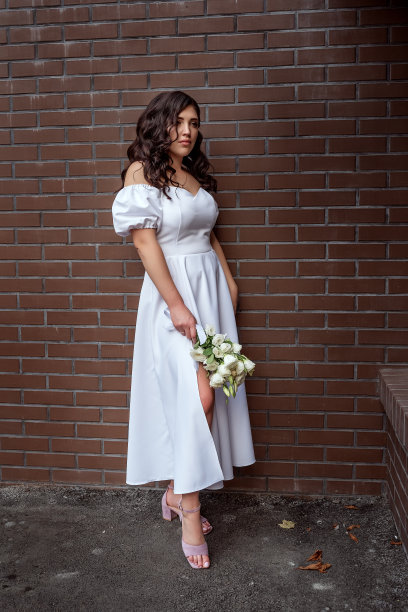 悲伤的时髦女孩。美国新娘的肖像在白色豪华礼服与花束对着一堵棕色砖墙。复古风格的结婚照图片下载