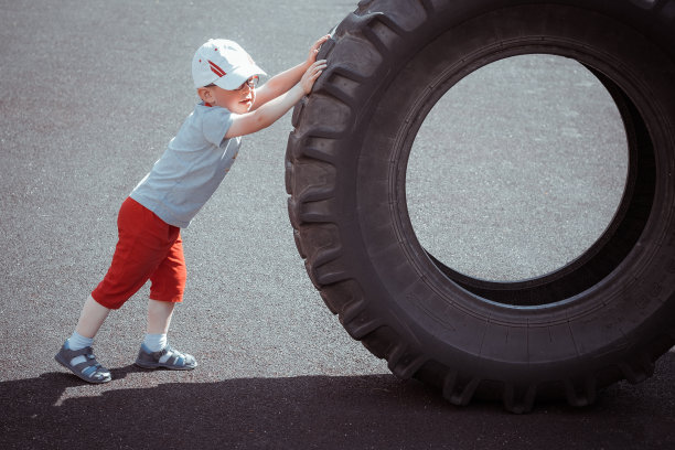 小男孩滚动一辆大卡车的轮子，锻炼身体图片下载