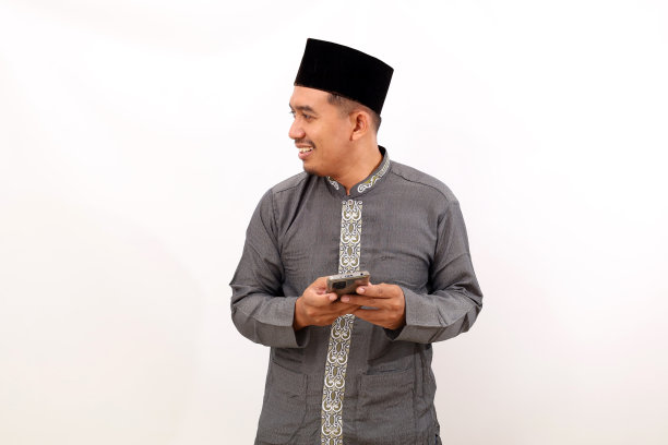 亚洲穆斯林男子一边看一边拿着手机。隔离在白色背景与复制空间图片下载