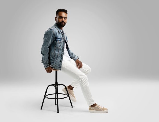 英俊的年轻非裔美国人坐在凳子上，在工作室摆姿势孤立图片下载