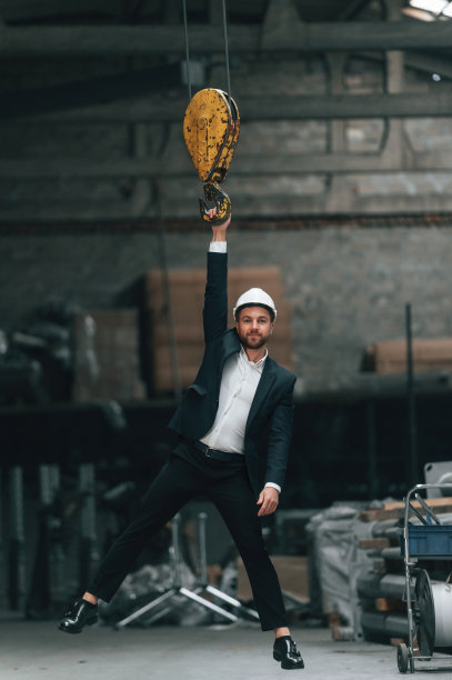 吊在吊车钩上。身着黑色正装的经理在工厂图片下载