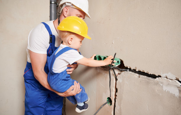 男人和孩子在墙上安装电源插座。图片下载