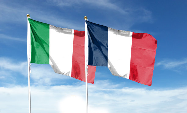 法国国旗和意大利国旗映衬着多云的天空。在天空中舞动图片下载
