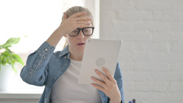 沮丧的年轻女子在室内平板电脑上对失去的反应图片下载