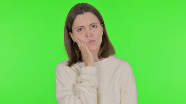 绿色背景下有牙痛的年轻女子图片下载