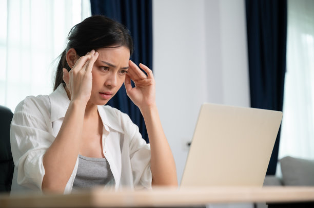 办公室综合症。劳累过度的年轻亚洲妇女感觉头痛，电脑笔记本电脑工作后视力问题。压力大的年轻女性在家里饱受疲劳之苦图片下载