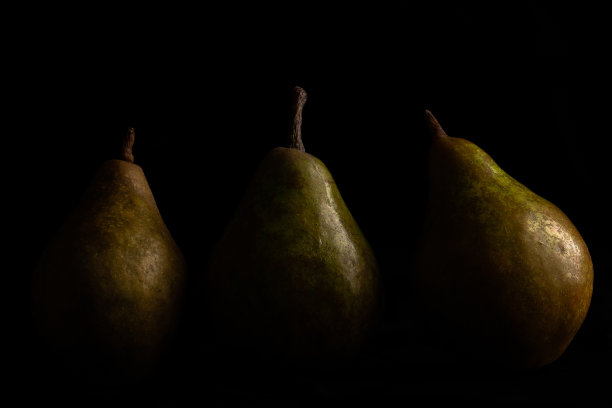 特写三个绿色的梨从孤立在黑色背景的一侧变暗图片下载