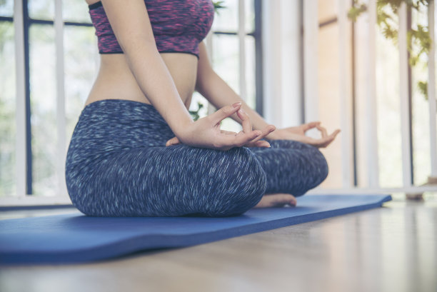 Asana瑜伽美丽的女人微笑在运动服坐在瑜伽垫上，家庭健身快乐的健康生活方式。微笑的亚洲妇女做体式瑜伽身体，腿伸展在客厅家庭健身运动图片下载
