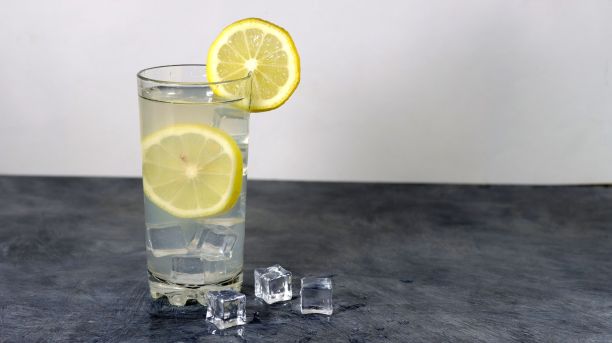 一杯杜松子酒柠檬鸡尾酒和冰立方放在灰色的桌子上图片下载