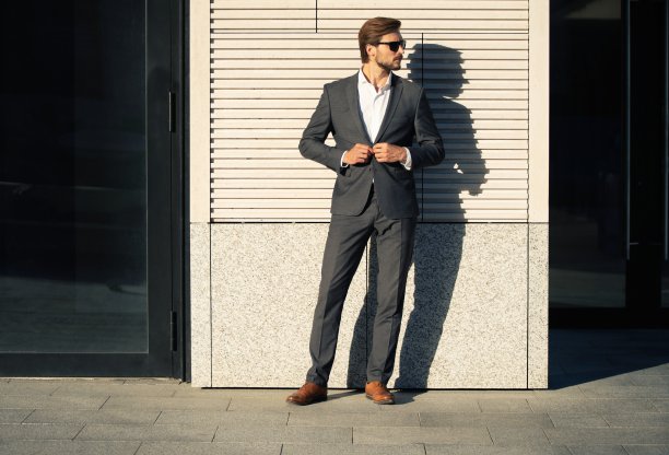 穿着经典西装的优雅帅哥站在办公楼附近。图片下载