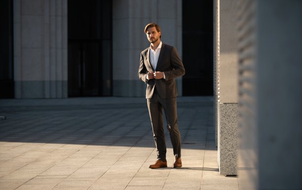 穿着经典西装的优雅帅哥站在办公楼附近。图片下载