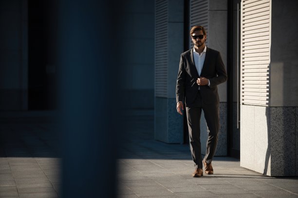 穿着经典西装的优雅帅哥站在办公楼附近。图片下载