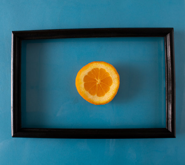 在蓝色的墙上挂着一幅黑色相框里装着一个健康的橙子的画图片下载