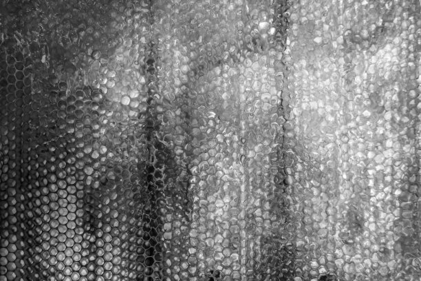 一滴蜜蜂蜜从充满花蜜的六角形蜂巢中滴下图片下载