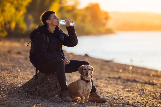 一个女人带着她的狗坐在河边喝水图片下载