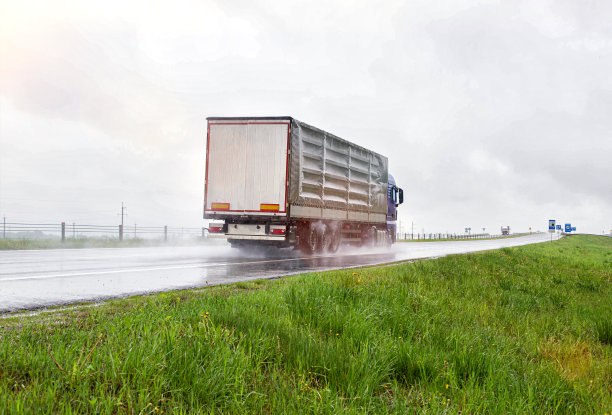 一辆带半挂车的卡车在雨天滑滑的路上运送货物。汽车货物运输。文本复制空间图片下载