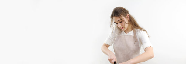 横幅烹饪食物坩埚模具妇女女孩靠在桌子上，在白色背景的横幅上切割女学生在围裙里烹饪什么东西图片下载